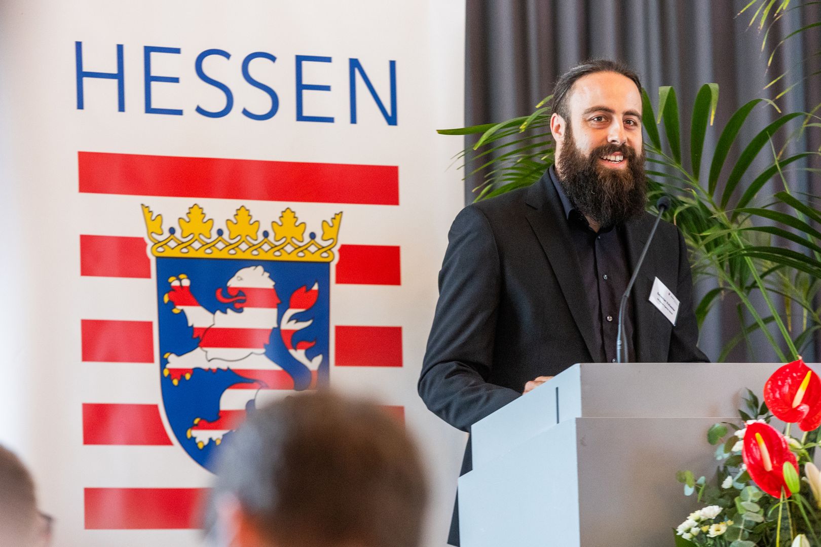 Sebastian Vollweiler von der Geschäftsstelle „Nachhaltige Stadtentwicklung in Hessen“ steht am Rednerpult.