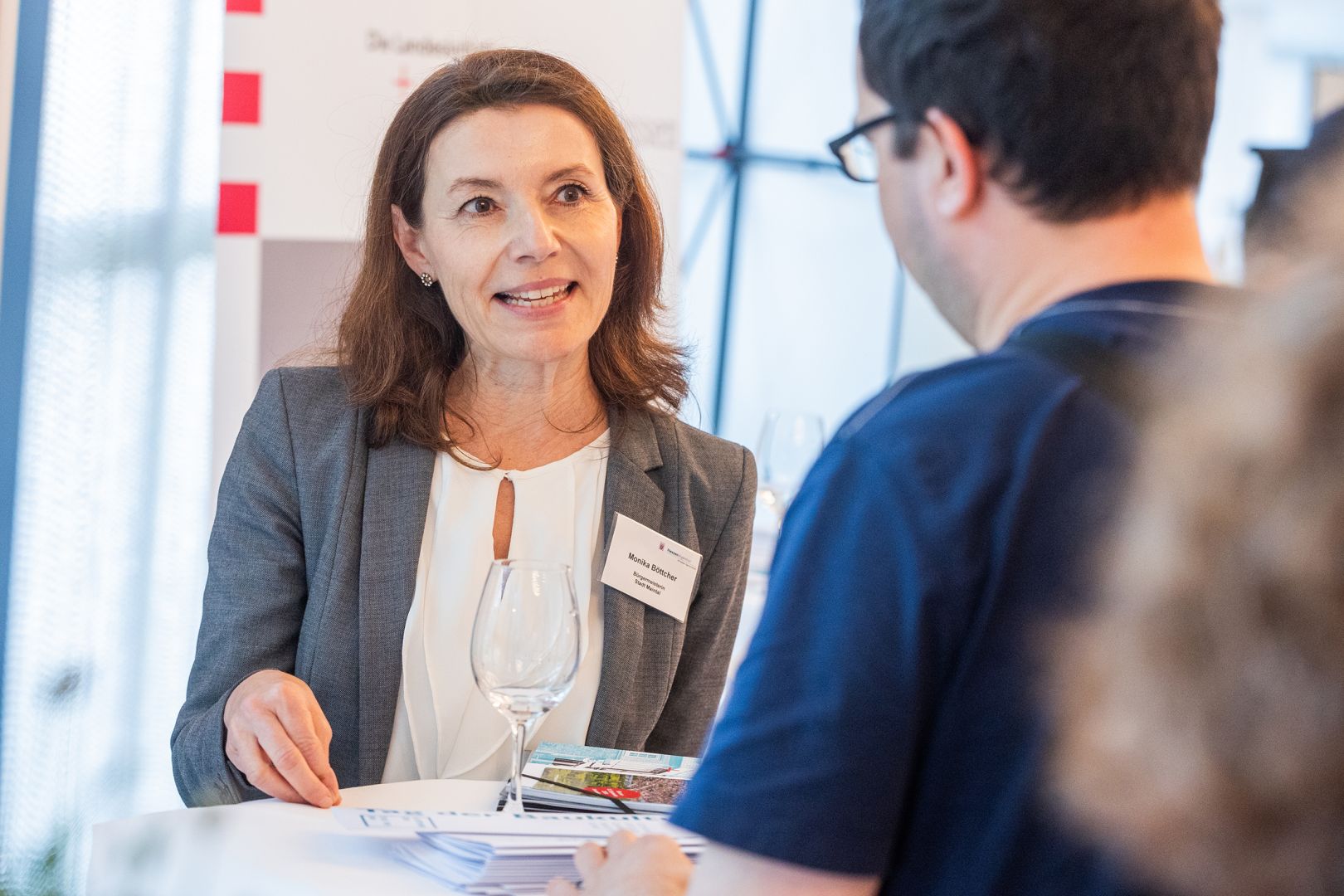 Monika Böttcher, Bürgermeisterin von Maintal, spricht mit einem Mann an einem Tisch.